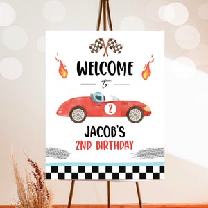 May include: Welcome to Jacob's 2nd Birthday party sign with a red race car, checkered flags, and flames.