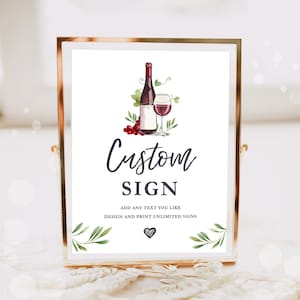 May include: A white sign with a gold frame featuring a watercolor illustration of a bottle of wine and a glass of wine. The sign says "Custom Sign" and "Add any text you like. Design and print unlimited signs".