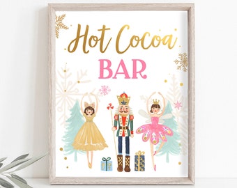 May include: A framed print with the words "Hot Cocoa Bar" in gold script and pink block letters. The image features illustrations of a ballerina, a nutcracker, and a ballerina, with snowflakes and Christmas trees.