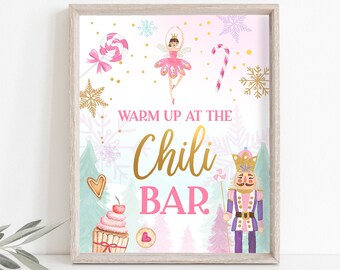 May include: A framed print with a winter theme, featuring a ballerina, nutcracker, and candy cane. The text "Warm Up At The Chili Bar" is displayed in gold and pink. Decorative elements include snowflakes, trees, and a cupcake.