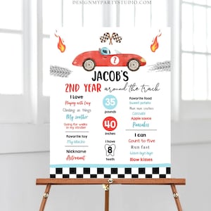 May include: A red and white race car themed printable birthday sign for a child's second birthday. The sign includes the child's name, "Jacob's 2nd Year Around the Track", and details about the child's age, weight, height, favorite foods, and activities.