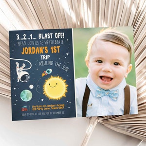 May include: A blue and orange space-themed birthday invitation for a boy's first birthday party. The invitation features an astronaut, a rocket, a planet, and a sun. The text on the invitation reads "3...2...1... BLAST OFF! Please join us as we celebrate Jordan's 1st Trip Around the Sun. Jan 12th 1 to 4 pm at Jordan's house 123 Party Lane, Texas 4567 RSVP to Amy at 123.456.109 by December 12. DesignMyPartyStudio.com".