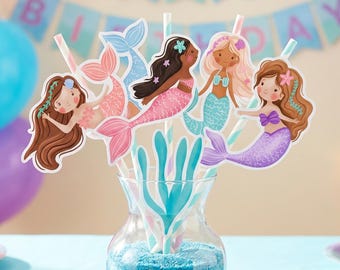 May include: A set of paper straws featuring colorful mermaid cutouts with various hair colors and tail designs, including a blue seaweed cutout, all arranged in a clear glass vase filled with blue sand for a decorative party display.