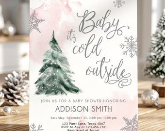 May include: A rectangular baby shower invitation card featuring a watercolor green pine tree, soft pink watercolor splashes, and silver snowflake illustrations. The text reads: Baby it's cold outside, JOIN US FOR A BABY SHOWER HONORING ADDISON SMITH.
