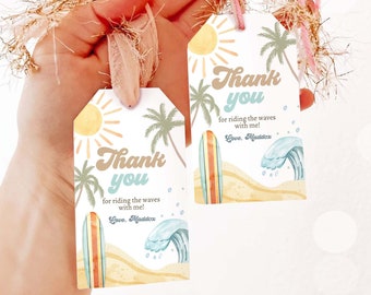 May include: Two thank you tags with a beach theme. The tags are white with a yellow sun, palm trees, a surfboard, and a blue wave. The text on the tags reads "Thank you for riding the waves with me! Love, Maddox".