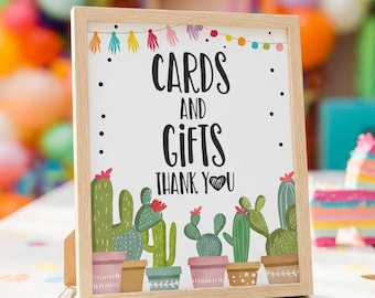 May include: A rectangular wooden frame containing a white sign with the black text CARDS AND GIFTS THANK YOU. The sign features a colorful illustration of various green cacti in pots along the bottom and a string of multi-colored tassels at the top.