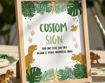 May include: A light wood frame containing a white sign with green tropical leaf illustrations, gold dinosaur graphics, and dinosaur footprint icons. The text reads: CUSTOM SIGN, ADD ANY TEXT YOU LIKE, DESIGN & PRINT UNLIMITED SIGNS in dark green and black.