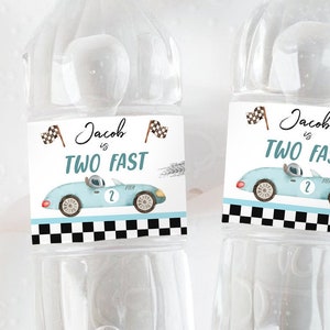 Puede incluir: Dos botellas de agua con etiquetas que dicen "Jacob is Two Fast" y presentan un coche de carreras azul de dibujos animados con una bandera a cuadros. Las etiquetas son negras y blancas con texto marr&oacute;n.