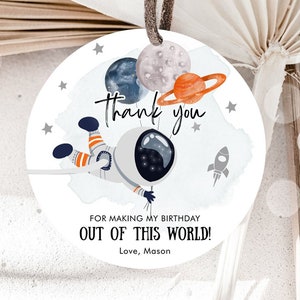 May include: Round white thank you tag with an astronaut holding balloons shaped like planets. The tag says "Thank you" and "For making my birthday out of this world! Love, Mason".