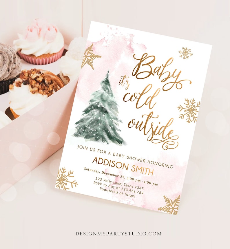 May include: A rectangular baby shower invitation card featuring a watercolour green Christmas tree, gold foil snowflakes, and pink watercolour accents. The text reads: Baby it's cold outside, JOIN US FOR A BABY SHOWER HONORING ADDISON SMITH, Saturday, December 22, 3:00 pm - 4:00 pm, 123 Party Lane, Texas 4567, RSVP to Amy at 123.456.789, Registered at Target.