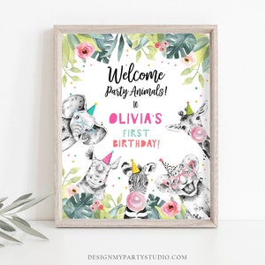 May include: A framed print with watercolor illustrations of party animals, including an elephant, rhino, zebra, giraffe, and lion. The text reads "Welcome Party Animals! to OLIVIA'S FIRST BIRTHDAY!" surrounded by floral and confetti accents.