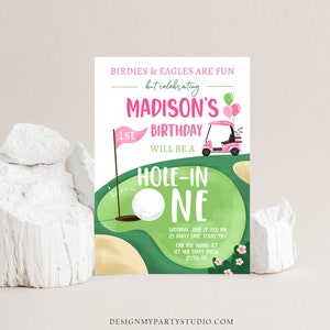 May include: A birthday invitation with a golf theme, featuring a green golf course design. The invitation includes the text "Madison's 1st Birthday" and "Hole-in-One". A pink golf cart and golf ball are also shown. The invitation is set against a white background.