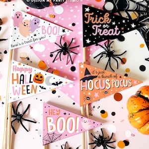 May include: A collection of Halloween-themed pennant flags with various designs and phrases, including "Trick or Treat" and "Hocus Pocus." The flags are in black, orange, and pink, with illustrations of ghosts, spiders, and pumpkins. Black plastic spiders and confetti are scattered around the flags.
