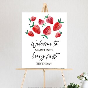 Peut inclure: Affiche de bienvenue pour le premier anniversaire de Madeline, avec un fond blanc et des fraises rouges en aquarelle.