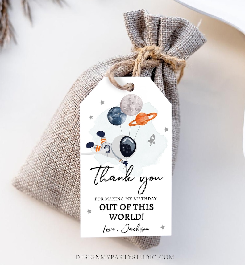 May include: A white thank you tag with a watercolor illustration of an astronaut holding onto balloons shaped like planets. The text on the tag reads "Thank you for making my birthday out of this world! Love, Jackson".