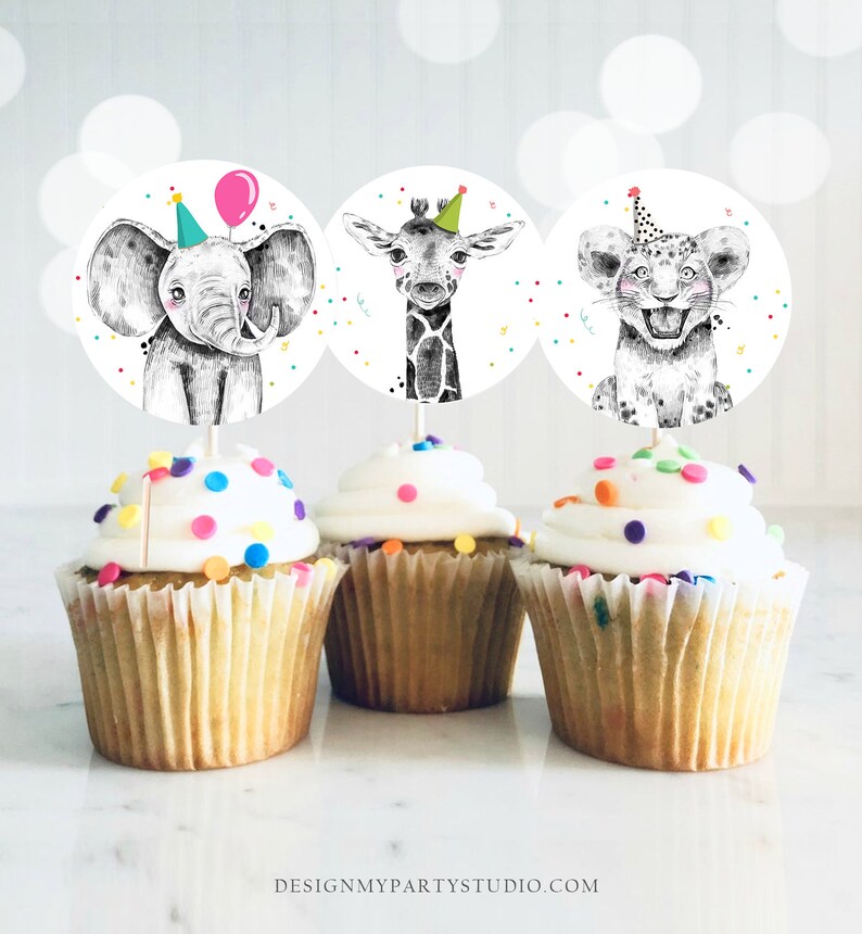 May include: Three cupcake toppers featuring a black and white elephant, giraffe, and lion wearing party hats. The toppers are on top of cupcakes with white frosting and colorful sprinkles.