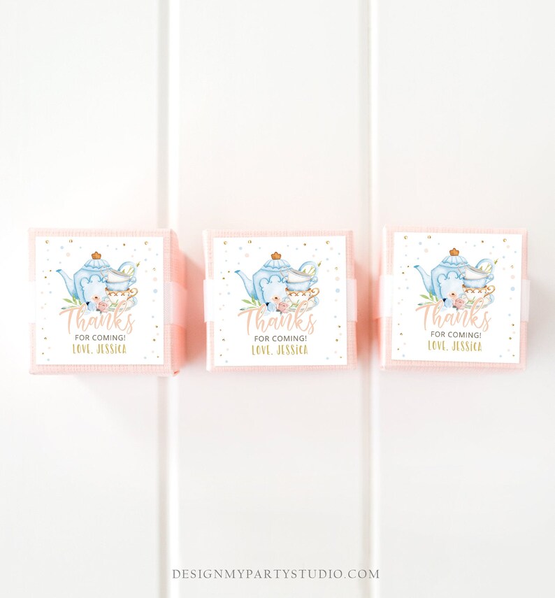 May include: Three pink favour boxes with white labels. The labels feature a blue teapot and teacups with floral accents. The text on the labels reads "Thanks for coming! Love, Jessica."