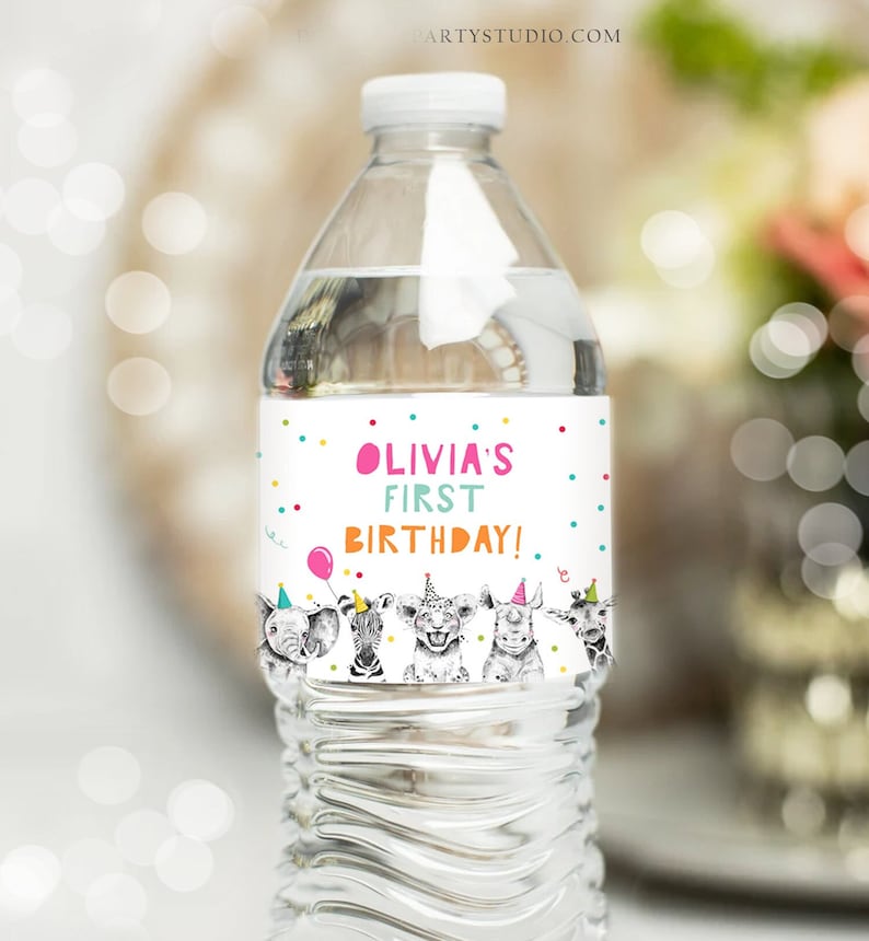 May include: Water bottle label with a white background and colorful confetti. The label features a pink, blue, and green text that reads "Olivia's First Birthday!" with a cartoon image of five animals wearing party hats.