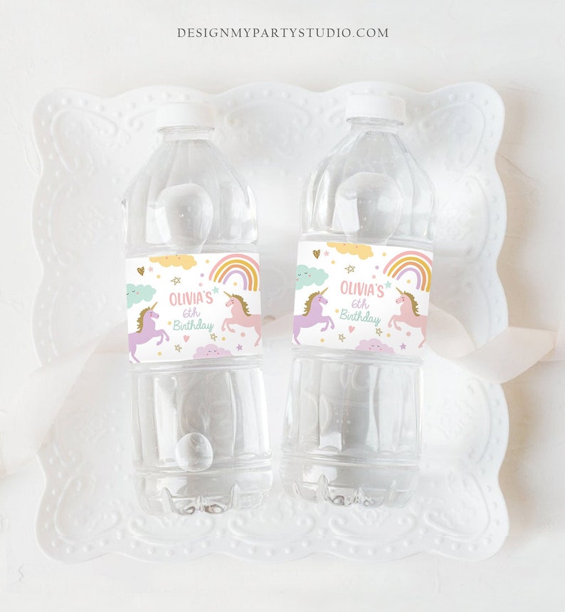 May include: Two clear plastic water bottles with personalized labels. The labels are white with a rainbow, clouds, stars, and a unicorn. The text on the labels reads "Olivia's 6th Birthday".