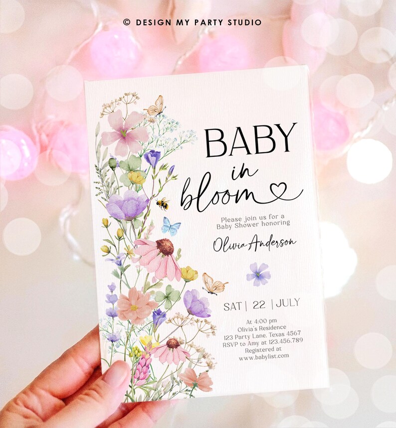 May include: A baby shower invitation with a watercolor floral design. The text reads "Baby in Bloom" with a heart and "Please join us for a Baby Shower honoring Olivia Anderson". The invitation includes the date, time, location, RSVP information, and website for the baby shower.