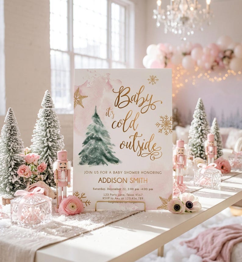May include: A rectangular baby shower invitation sign featuring a watercolour pink background, a green pine tree illustration, and gold foil text that reads Baby it's cold outside, JOIN US FOR A BABY SHOWER HONORING ADDISON SMITH, Saturday, December 22, 3:00 pm - 4:00 pm, 123 Party Lane, Texas 4567, RSVP to Amy at 123.456.789.