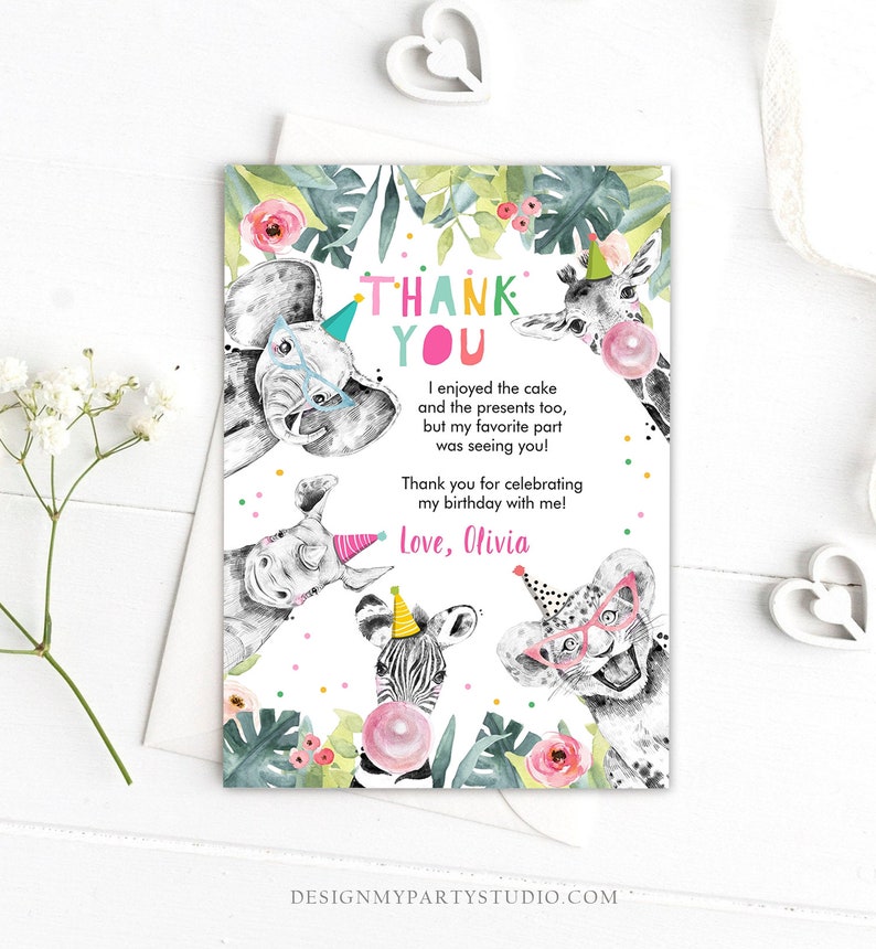 May include: Thank you card with a jungle theme. The card features a colorful thank you message, a pink bubble, and illustrations of a zebra, giraffe, elephant, rhinoceros, and a leopard wearing party hats and glasses. The text on the card reads "Thank You. I enjoyed the cake and the presents too, but my favorite part was seeing you! Thank you for celebrating my birthday with me! Love, Olivia."