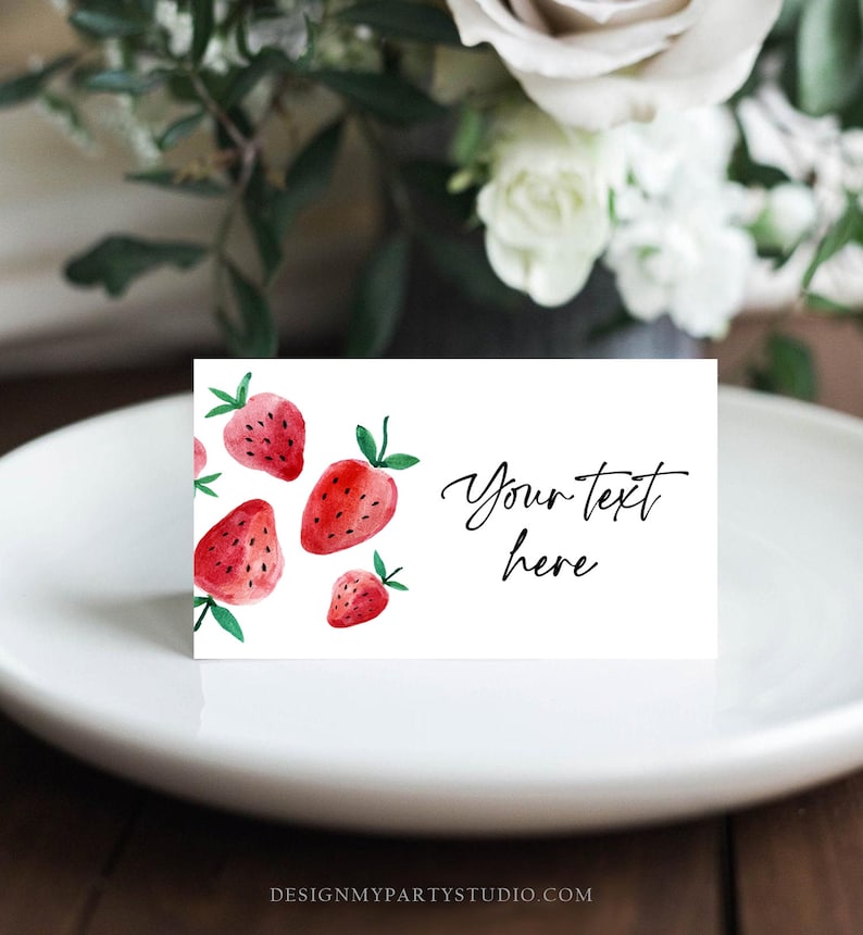 May include: White place card with a watercolor design of red strawberries. The text "Your text here" is written in black cursive.