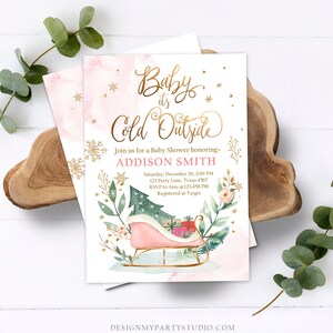 May include: Baby shower invitation with the text "Baby it's Cold Outside" in gold script. The invitation features a pink watercolor background, a pink sleigh with gifts, and floral and snowflake accents. The invitation is for Addison Smith.