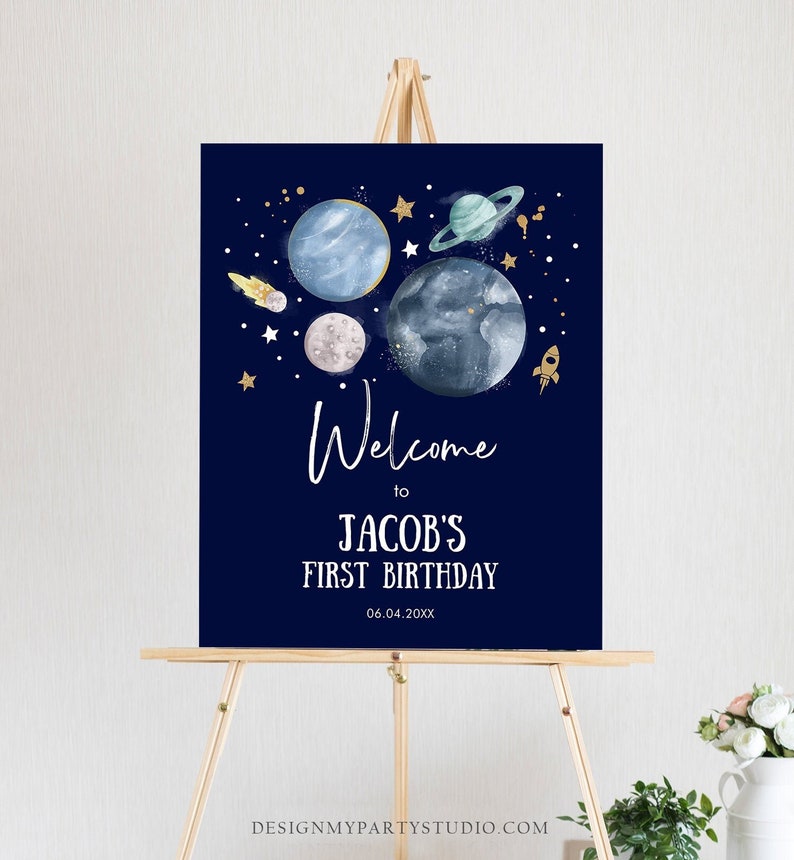May include: A blue welcome sign with gold stars and planets, a rocket, and the text "Welcome to Jacob's First Birthday 06.04.20XX".