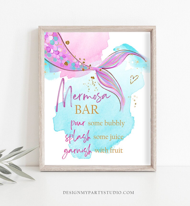 May include: A printable sign with a mermaid tail design and the text "Mermosa Bar" in pink and gold lettering. The sign instructs to "pour some bubbly, splash some juice, garnish with fruit".