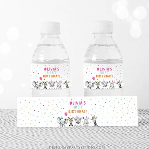 May include: Water bottle labels with a colorful polka dot background and a black and white illustration of animals wearing party hats. The text on the label reads "Olivia's First Birthday!"