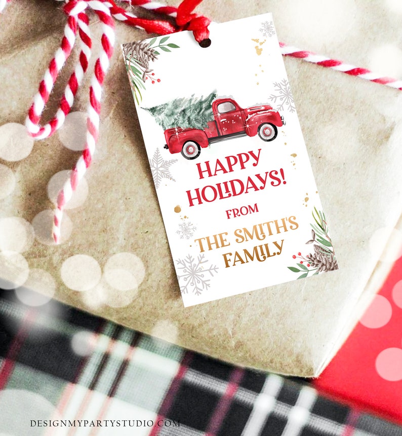 Puede incluir: Una etiqueta de regalo con un cami&oacute;n rojo vintage que transporta un &aacute;rbol de Navidad. La etiqueta dice "Happy Holidays! From The Smith's Family" con detalles de copos de nieve y pino. La etiqueta est&aacute; atada a un regalo envuelto.