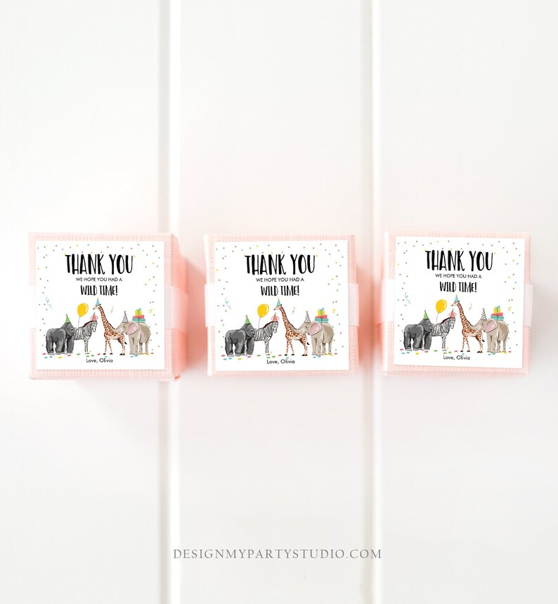 Op de afbeelding: Drie roze cadeauboxen met witte etiketten. De etiketten hebben een zwart-witte illustratie van een giraffe, zebra, olifant en aap die feestmutsen dragen. De tekst op de etiketten luidt "Bedankt We hopen dat je een wilde tijd hebt gehad! Liefs, Olivia."
