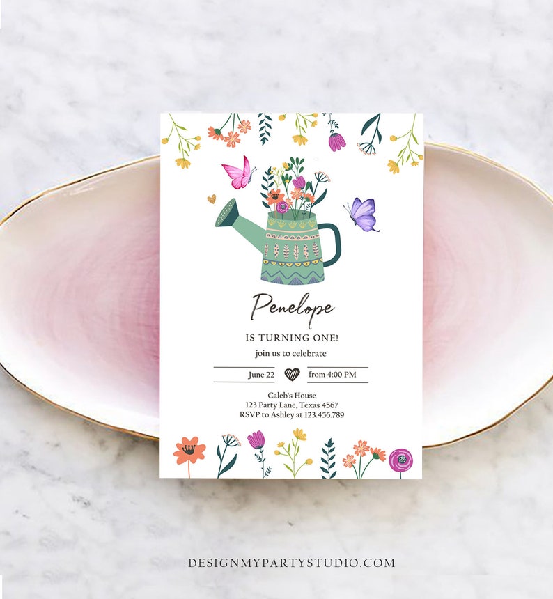 May include: A white invitation card with a green watering can filled with colorful flowers and butterflies. The text on the card reads "Penelope is turning one!" with details about the party, including the date, time, location, and RSVP information.