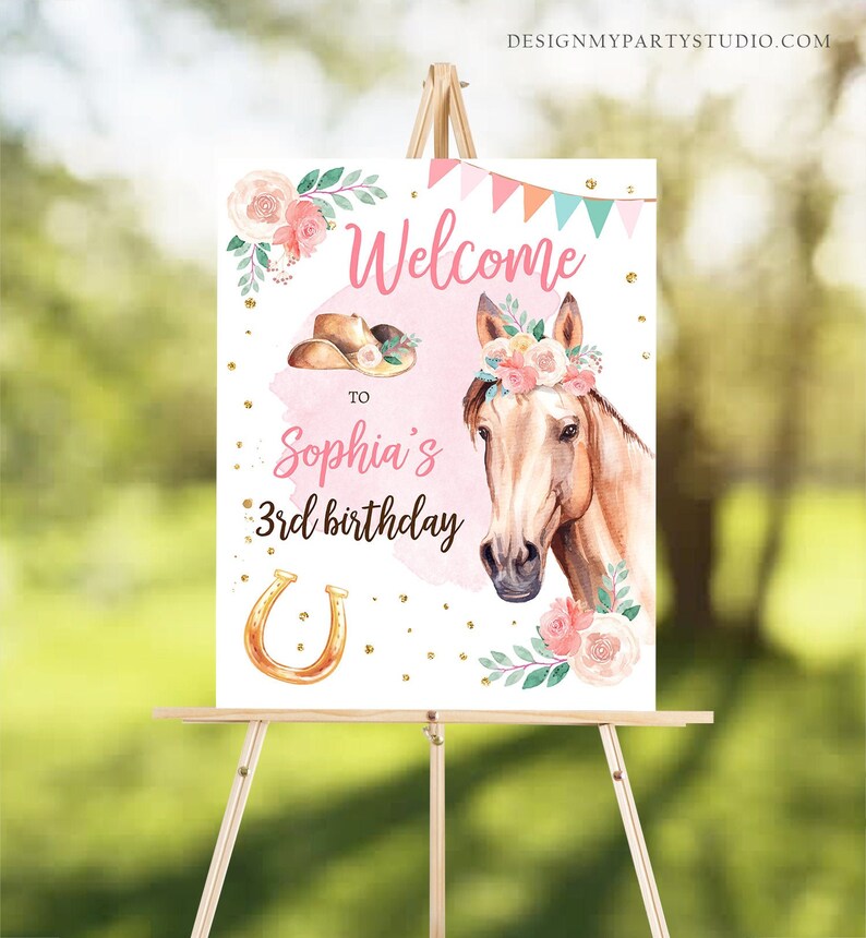 May include: Welcome to Sophia's 3rd birthday sign with a pink background, gold glitter, a brown horse with a floral crown, a cowboy hat, and a gold horseshoe.