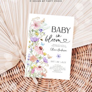 May include: A floral baby shower invitation with a watercolor design of pink, purple, and yellow flowers. The text reads "Baby in Bloom" with a heart and "Please join us for a Baby Shower honoring Olivia Anderson". The date and time of the shower are listed as "Sat 22 July at 4:00 pm" along with the address and RSVP information.