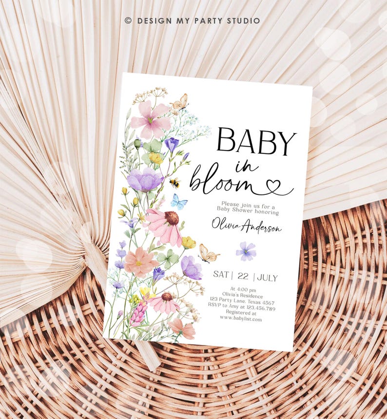 May include: A floral baby shower invitation with a watercolor design of pink, purple, and yellow flowers. The text reads "Baby in Bloom" with a heart and "Please join us for a Baby Shower honoring Olivia Anderson". The date and time of the shower are listed as "Sat 22 July at 4:00 pm" along with the address and RSVP information.