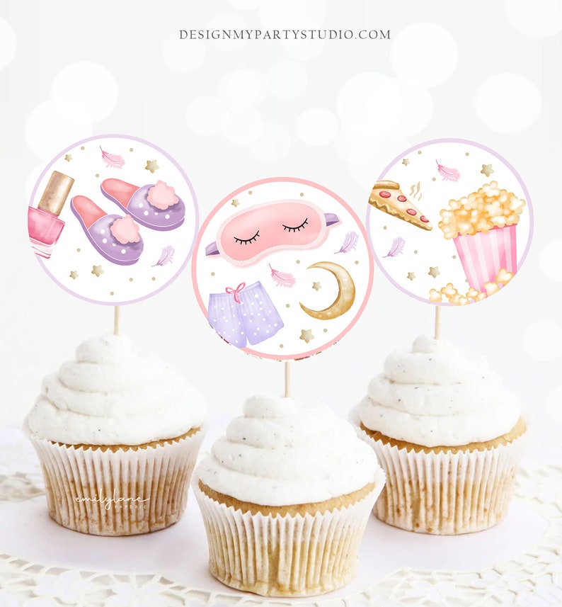 May include: Three cupcake toppers with a sleep over theme. The toppers feature a sleep mask, pajamas, slippers, pizza, and popcorn. The toppers are on top of cupcakes with white frosting.
