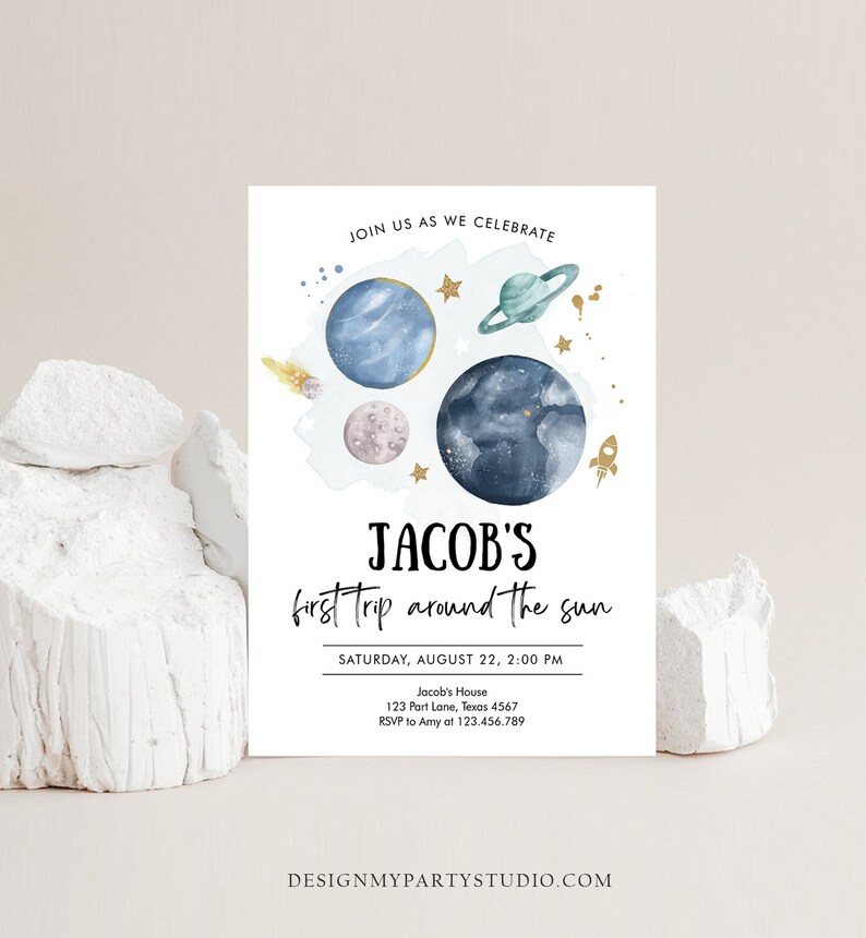 May include: A blue and white invitation with a watercolor illustration of planets and stars. The text reads "Join us as we celebrate Jacob's first trip around the sun. Saturday, August 22, 2:00 PM. Jacob's House, 123 Part Lane, Texas 4567. RSVP to Amy at 123.456.789. DesignMyPartyStudio.com"