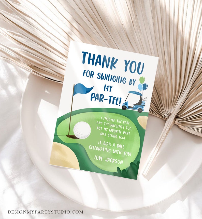May include: A thank you card with a golf theme. The card features a golf course illustration with a golf ball, flag, and golf cart. Text on the card reads "Thank You for Swinging by My Par-Tee!" and "Love, Jackson."