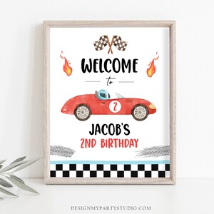 May include: A printable welcome sign for a 2nd birthday party with a red race car, checkered flags, and flames. The sign says "Welcome to Jacob's 2nd Birthday".