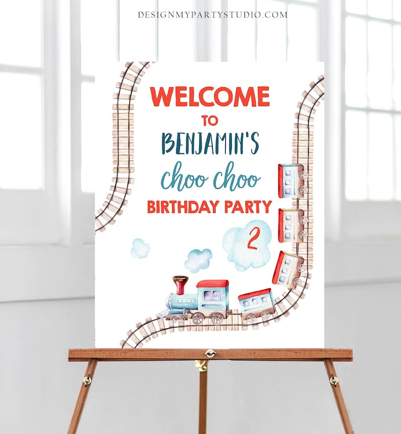 May include: Welcome to Benjamin's Choo Choo Birthday Party sign with a blue and red train on a brown track with white clouds. The number 2 is written on a cloud.