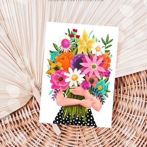 Op de afbeelding: Een kleurrijk boeket bloemen in verschillende tinten roze, paars, geel, oranje en wit, vastgehouden door een persoon die een zwart-wit gebloemde jurk draagt.