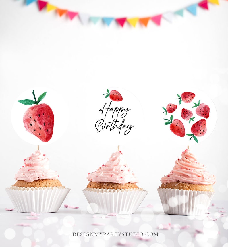 K&ouml;nnte beinhalten: Drei rosa glasierte Cupcakes mit wei&szlig;en Cupcake-F&ouml;rmchen. Jeder Cupcake hat einen runden, wei&szlig;en Papier-Topper mit einem Aquarell-Erdbeer-Design. Der mittlere Topper sagt "Happy Birthday" in schwarzer Schrift.