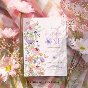May include: A floral-themed first birthday invitation with a watercolor design featuring pink, purple, and yellow flowers. The text reads "She's a Wild One" and includes details for the party, including the date, time, and location.