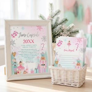 May include: A white distressed frame containing a Time Capsule sign with pink and blue holiday graphics, including a nutcracker and ballerina. Next to it is a white woven basket holding a stack of lined stationery cards labeled Dear Abigail.