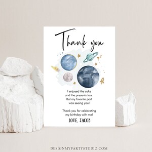 May include: A white thank you card with a space-themed design. The card features illustrations of planets, stars, and a rocket. Text includes "Thank you", a personal message, and "LOVE, JACOB". The card is designed for a birthday celebration.