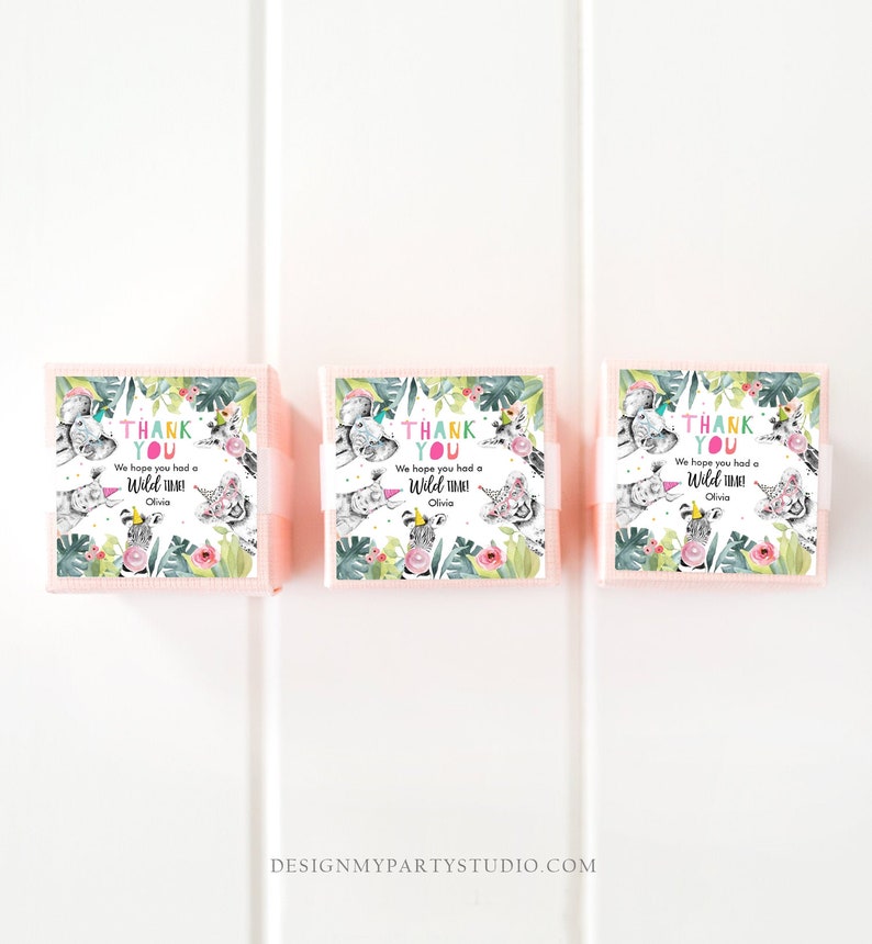 May include: Three pink favor boxes with a jungle-themed design. Each box features a watercolor illustration of various animals, including a zebra, tiger, and elephant, with the text "THANK YOU" and "We hope you had a Wild Time!" in colorful lettering.