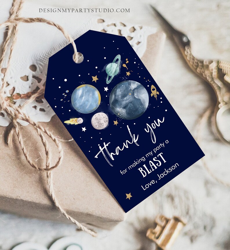 May include: A navy blue thank you tag with a space theme. It features planets, stars, and a rocket ship. The text reads "Thank you for making my party a BLAST. Love, Jackson."