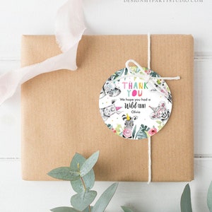 May include: A gift wrapped in brown paper with a white string and a round tag. The tag features a watercolor design with the words "THANK YOU" and "We hope you had a Wild time!" along with animal illustrations.